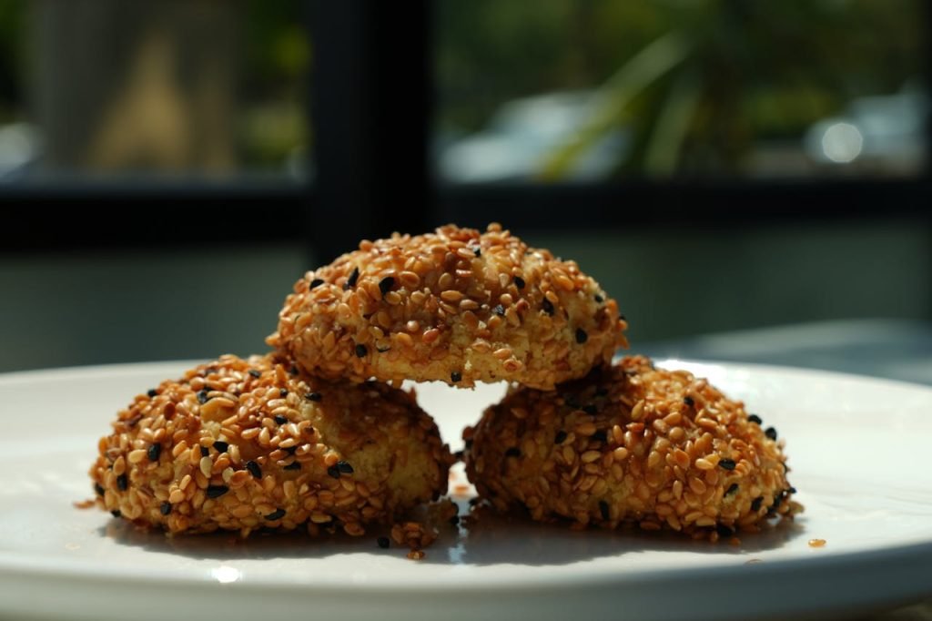 Close-up of freshly baked sesame seed cookies stacked on a plate.